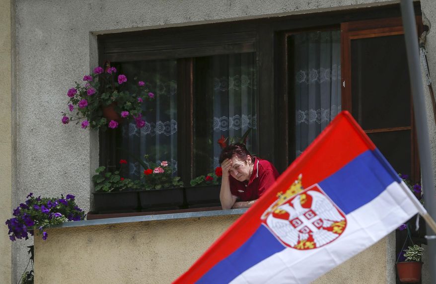 A woman standing at a balcony looks at a protest against Kosovo police action in the northern Serb-dominated part of ethnically divided town of Mitrovica, Kosovo, Wednesday, May 29, 2019. Russia and Serbia have blamed NATO and the West for an armed raid by Kosovo police in the Serb dominated north of Kosovo when a Russian U.N. employee was among more than two dozen people arrested in what Kosovo says was an anti-organized crime operation. (AP Photo/Visar Kryeziu)