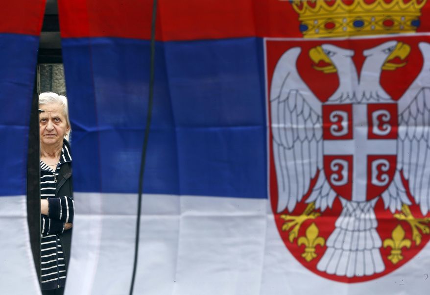 A Kosovo Serb woman is framed by Serbian flags as she attends a protest against Kosovo police action in the northern Serb-dominated part of ethnically divided town of Mitrovica, Kosovo, Wednesday, May 29, 2019. Russia and Serbia have blamed NATO and the West for an armed raid by Kosovo police in the Serb dominated north of Kosovo when a Russian U.N. employee was among more than two dozen people arrested in what Kosovo says was an anti-organized crime operation. (AP Photo/Visar Kryeziu)