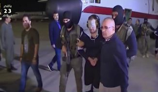 In this frame grab from Egyptian State Television, a blindfolded Hisham el-Ashmawi, a prominent Egyptian militant is escorted by Egyptian military officers and placed in a vehicle after being taken off a military plane at an airport in Cairo, Egypt, Wednesday, May 29, 2019. El-Ashmawi was captured last October in the Libyan city of Derna, a longtime bastion of Islamic militants, by commander Khalifa Hifter&#x27;s self-styled Libyan National Army. (Egyptian State Television via AP)