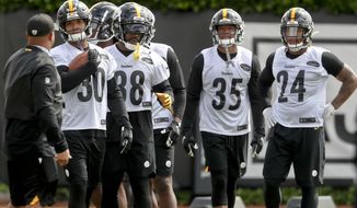 FILE - This May 21, 2019, file photo shows Pittsburgh Steelers running backs coach Eddie Faulkner, left, instructing James Conner (30), Jaylen Samuels (38), Travon McMillian (35), and Benny Snell Jr. (24) during an NFL football practice in Pittsburgh. Conner doesn&#39;t have to answer questions about Le&#39;Veon Bell anymore. He is firmly entrenched as the starter entering his third season but welcomes the chance to share the load with Jaylen Samuels and rookie Benny Snell Jr. (AP Photo/Keith Srakocic, File)
