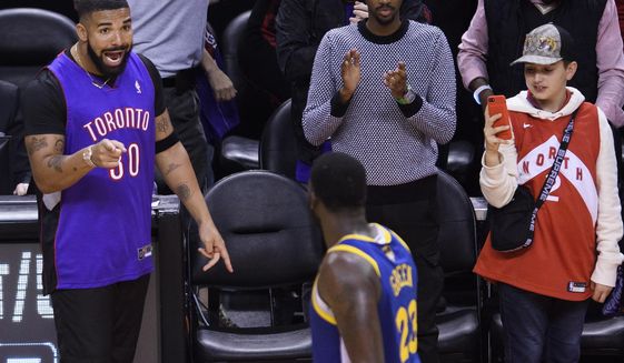 Rapper Drake, left,, says something to Golden State Warriors forward Draymond Green (23) after the Toronto Raptors defeated the Warriors in Game 1 of basketball’s NBA Finals, Thursday, May 30, 2019, in Toronto. (Nathan Denette/The Canadian Press via AP)