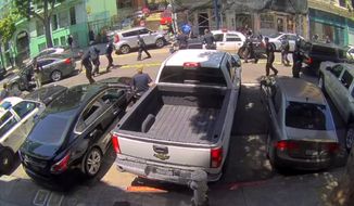 This photo taken from video from a surveillance camera mounted outside the San Francisco Police Department&#x27;s Tenderloin station shows officers trying to intercept a stolen silver Kia SUV, at top left, during a wild police chase through busy San Francisco neighborhoods that ended with a female driver&#x27;s arrest, Wednesday, May 29, 2019. Police say the Kia hit several cars and pedestrians, and injured multiple people, before police caught up with it in the South of Market neighborhood. (San Francisco Police Department via AP)