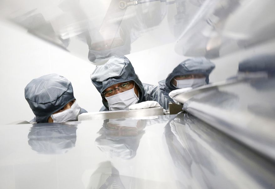 In this May 24, 2019, photo, workers talk at a composite materials manufacturing plant in Nantong in eastern China's Jiangsu province. China's factory activity fell into contraction territory in May amid an ongoing trade dispute with the U.S. that has seen higher tariffs slapped on Chinese exports. (Chinatopix via AP)