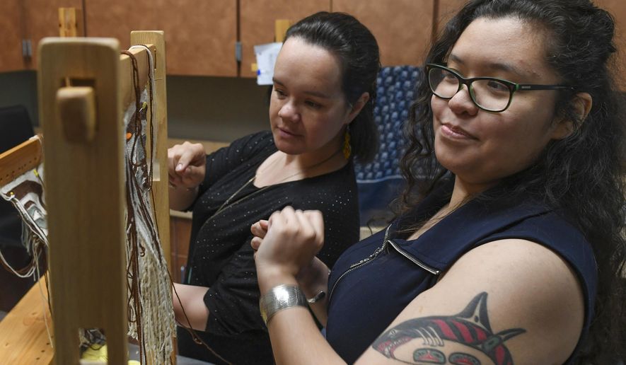 In this May 22, 2019 photo, Anastasia Hobson-George, right, works with weaver Lily Hope as the Artist-in-Residence at the Walter Soboleff Center in Juneau, Alaska. A Juneau artist is working to become the fifth person alive who knows how to make an increasingly rare type of traditional clothing. Tlingit weaver Hobson-George was recently announced as a winner of a Rasmuson Foundation Individual Artist Award, and she plans to use the $7,500 grant that comes with her project award to learn how to make a sleeved tunic that incorporates two types of indigenous weaving. (Michael Penn/The Juneau Empire via AP)