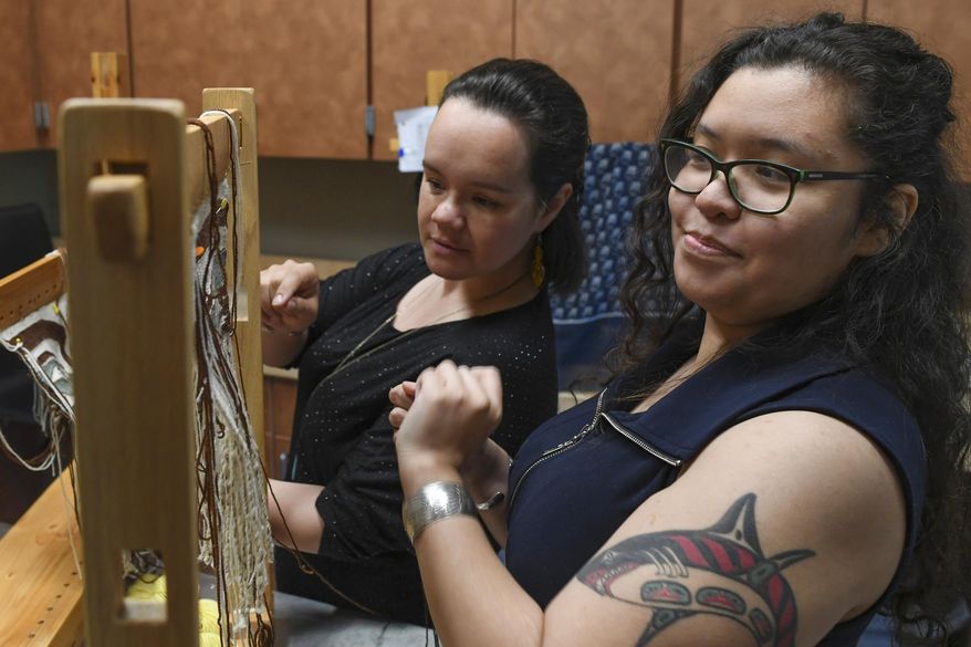 In this May 22, 2019 photo, Anastasia Hobson-George, right, works with weaver Lily Hope as the Artist-in-Residence at the Walter Soboleff Center in Juneau, Alaska. A Juneau artist is working to become the fifth person alive who knows how to make an increasingly rare type of traditional clothing. Tlingit weaver Hobson-George was recently announced as a winner of a Rasmuson Foundation Individual Artist Award, and she plans to use the $7,500 grant that comes with her project award to learn how to make a sleeved tunic that incorporates two types of indigenous weaving. (Michael Penn/The Juneau Empire via AP)