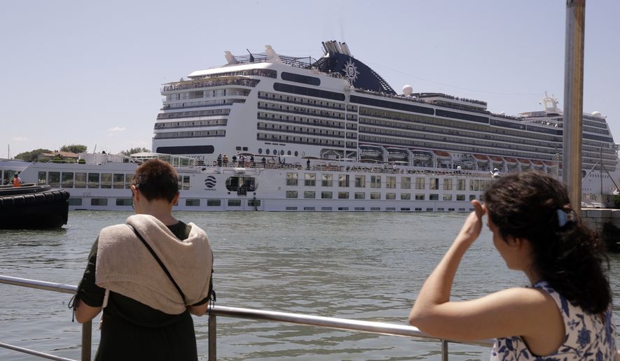 The tourist river boat that was struck by a towering cruise liner, foreground bottom, is dwarfed by the MSC Magnifica cruise liner passing by, in Venice, Italy, Sunday, June 2, 2019. The MSC Opera cruise ship has struck a dock and a tourist river boat on a busy canal in Venice. Italian media report that at least five people have been injured in the crash. (AP Photo/Luca Bruno)