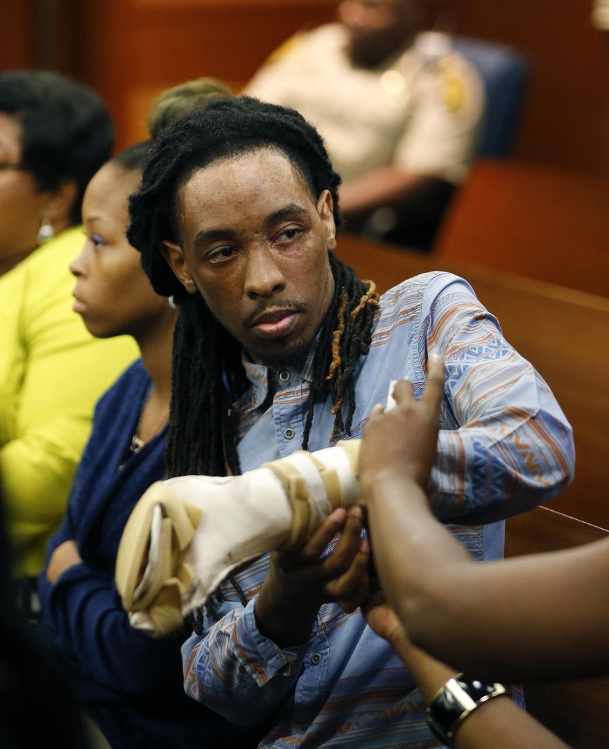 FILE - In this Aug. 24, 2016 file photo, burn victim Anthony Gooden gets help with his injured hand during a break in the trial for Martin Blackwell in Atlanta. Blackwell, who was convicted of throwing scalding water on a Gooden and his boyfriend while they slept, told one of them to “get out of my house with all that gay,” a victim testified, but he couldn’t be charged with a hate crime because the state has no such law. Georgia is one of only four states - along with South Carolina, Wyoming and Arkansas - without an official hate crimes law. (AP Photo/John Bazemore, File)