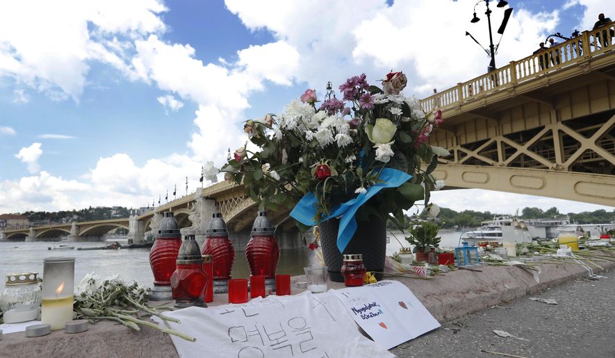 Flowers are laid next to the Margit Bridge where a sightseeing boat capsized in Budapest, Hungary, Sunday, June 2, 2019. Authorities said water levels in Budapest are expected to fall quickly in the coming days, helping efforts to salvage the wreckage that may still contain victims' bodies. (AP Photo/Laszlo Balogh)