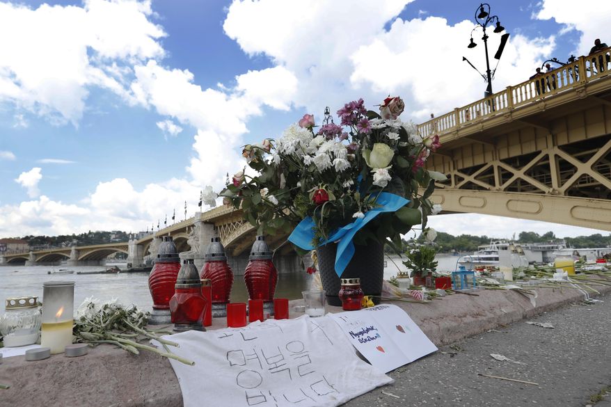 Flowers are laid next to the Margit Bridge where a sightseeing boat capsized in Budapest, Hungary, Sunday, June 2, 2019. Authorities said water levels in Budapest are expected to fall quickly in the coming days, helping efforts to salvage the wreckage that may still contain victims' bodies. (AP Photo/Laszlo Balogh)