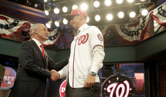 Major League Baseball Commissioner Rob Manfred, left, greets Jackson Rutledge, a right-handed pitcher from San Jacinto Junior College in Pasadena, Texas, onstage after Rutledge was elected No. 17 by the Washington Nationals in the first round of the Major League Baseball draft, Monday, June 3, 2019, in Secaucus, N.J. (AP Photo/Julio Cortez) **FILE**