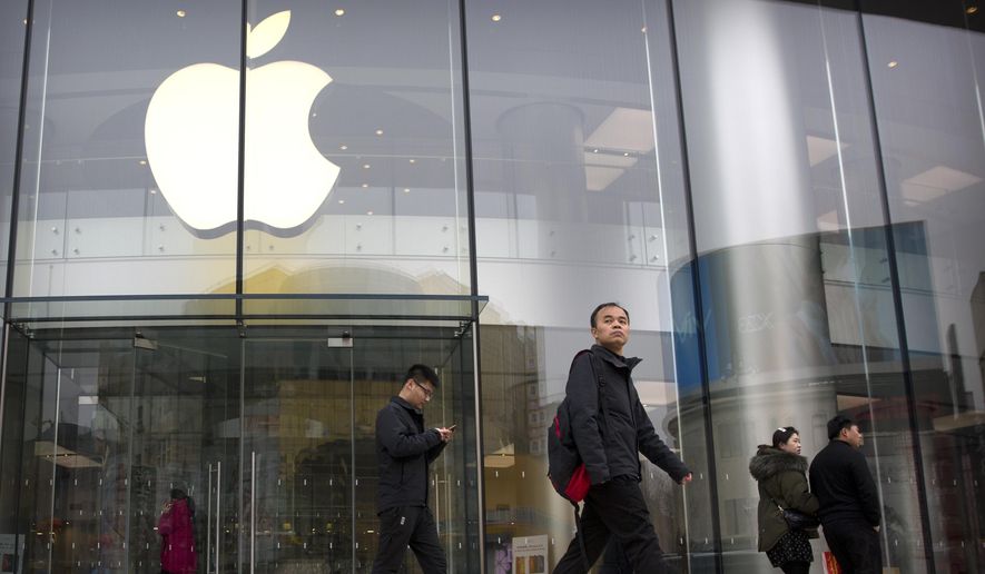 In this Feb. 26, 2019, file photo, people walk past an Apple store at an outdoor shopping street in Beijing. Apple will preview upcoming changes to its phone and computer software Monday, June 3 as it undergoes a major transition intended to offset eroding sales of its bedrock iPhone. The company’s software showcase is an annual rite. But Apple is currently grappling with its biggest challenge since its visionary co-founder, Steve Jobs, died nearly eight years ago. (AP Photo/Mark Schiefelbein, File) ** FILE **