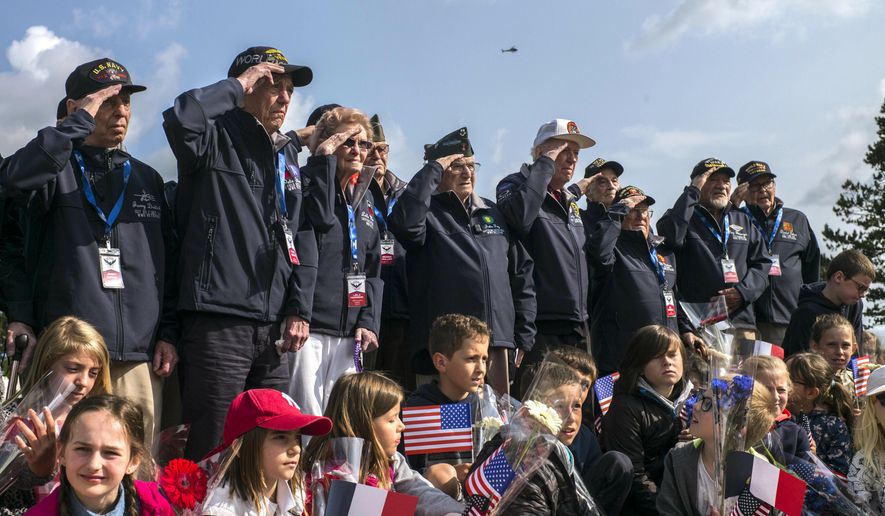 World War II veterans from the United States salute as they pose with local school children at the Normandy American Cemetery in Colleville-sur-Mer, Normandy, France, Monday, June 3, 2019. France is preparing to mark the 75th anniversary of the D-Day invasion which took place on June 6, 1944. (AP Photo/Rafael Yaghobzadeh)