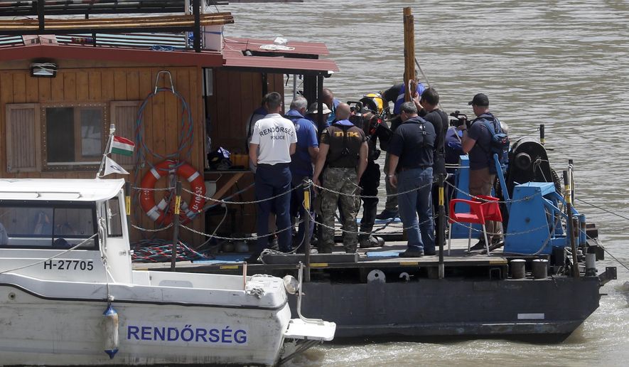 A diver, center, prepares to submerge into the Danube River under the Margaret Bridge during a search operation where a sightseeing boat capsized in Budapest, Hungary, Monday, June 3, 2019. Preparations for salvage efforts of a sunken tour boat in the Danube River have resumed in Budapest. The boat carrying South Korean tourists capsized and sank Wednesday night after colliding with a much larger river cruise ship near the Hungarian Parliament building. (AP Photo/Laszlo Balogh)