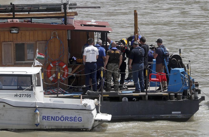 A diver, center, prepares to submerge into the Danube River under the Margaret Bridge during a search operation where a sightseeing boat capsized in Budapest, Hungary, Monday, June 3, 2019. Preparations for salvage efforts of a sunken tour boat in the Danube River have resumed in Budapest. The boat carrying South Korean tourists capsized and sank Wednesday night after colliding with a much larger river cruise ship near the Hungarian Parliament building. (AP Photo/Laszlo Balogh)