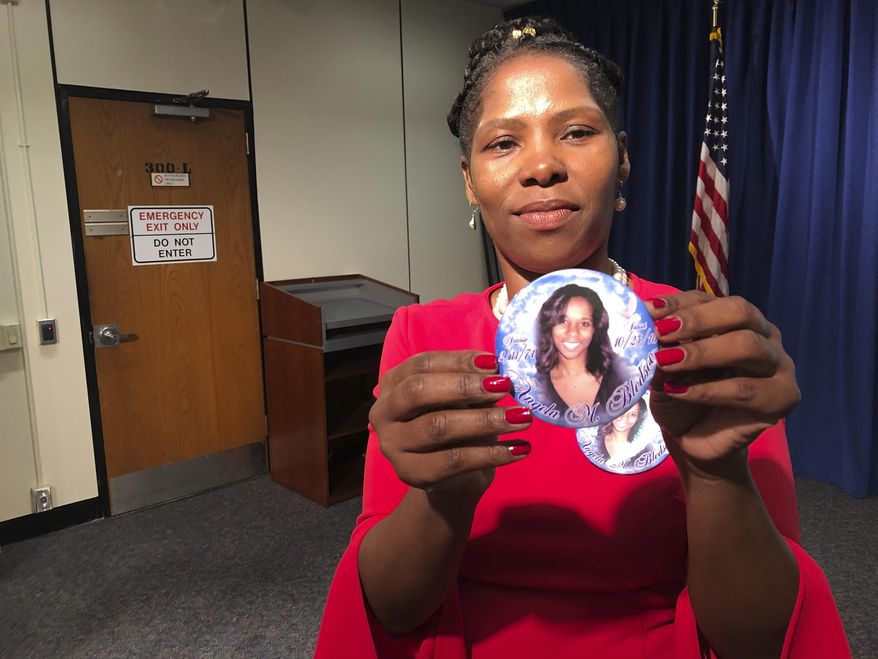 Lisa LaBoo of Eustis, Fla., holds up a button Monday depicting her sister, Angela Bledsoe, who was found shot to death in her home in Montclair, N.J., in October 2018. Bledsoe's boyfriend, James Ray III, has been charged with murder. He was arrested last fall after fleeing to Cuba. (AP Photo/ David Porter)