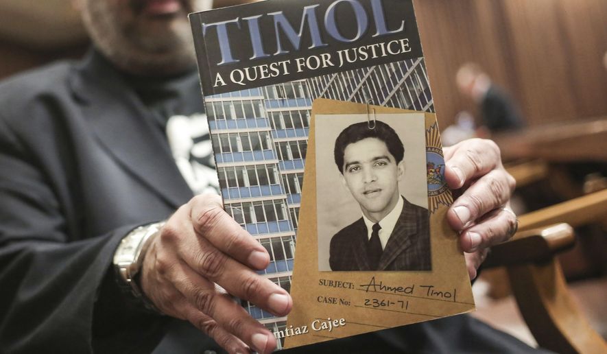 FILE - In this Thursday, Aug. 24, 2017 file photo, Imtiaz Cajee, nephew of Ahmed Timol, poses with his book "Timol, A Quest for Justice" in the North Gauteng High court in Pretoria, South Africa. A former South African police officer will face trial over the 1971 killing of an anti-apartheid activist after a court ruling that could lead to the prosecution of similar crimes. The high court in Johannesburg on Monday, June 3, 2019 dismissed 80-year-old Joao Rodrigues' application for a permanent stay of prosecution. (AP Photo, File)