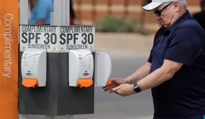 A fan get sunscreen from a complimentary kiosk before a spring training baseball game Wednesday, March 6, 2019, in Scottsdale, Ariz. (AP Photo/Elaine Thompson)
