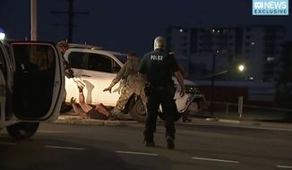 In this image made from video, police proceed to apprehend a suspect on the ground next to a white truck, Tuesday, June 4, 2019, in Darwin Australia. Media reports say a gunman has killed at least four people in the Australian city of Darwin. Northern Territory Police Duty Superintendent Lee Morgan says a 45-year-old man was in custody following Tuesday&#39;s shooting. (Australian Broadcasting Corporation via AP)