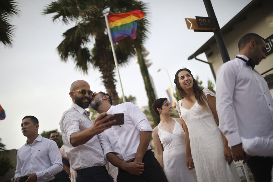 Gay couples prepare for a mass same-sex wedding in Tel Aviv, Israel, Tuesday, June 4, 2019. Hundreds of Israelis have participated in a mass wedding in Tel Aviv to demand the right to same-sex marriage ahead of the country's Gay Pride week, which involved an unofficial wedding ceremony for 23 gay couples, (AP Photo/Oded Balilty)