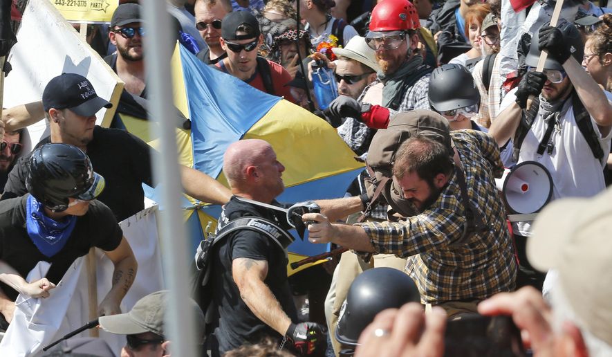 FILE - In this Aug. 12, 2017 file photo, white nationalist demonstrators clash with counter demonstrators at the entrance to Lee Park in Charlottesville, Va. Federal charges against three alleged members of a violent white supremacist group accused of inciting violence at California political rallies were dismissed Monday, June 3, 2019, by Judge Cormac J. Carney in U.S. District Court in Los Angeles, who found their actions amounted to constitutionally protected free speech. (AP Photo/Steve Helber, File)