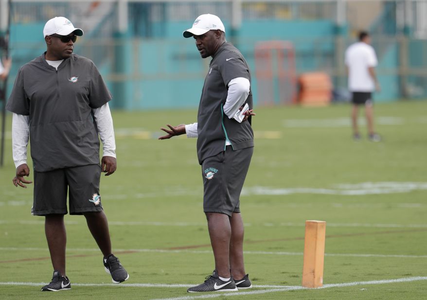 Miami Dolphins general manager Chris Grier, left, talks with head coach Brian Flores at the team's NFL football training facility, Tuesday, June 4, 2019, in Davie, Fla. (AP Photo/Lynne Sladky)