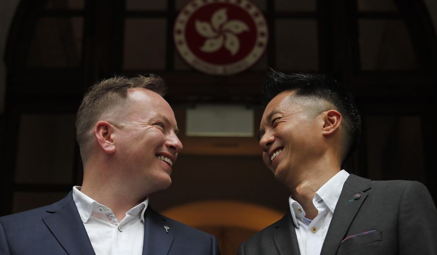 Angus Leung Chun-kwong, a senior immigration officer, right, and Scott Adams, a same-sex couple who married in New Zealand five years ago, pose for photographers outside the Court of Final Appeal in Hong Kong, Thursday, June 6, 2019. Hong Kong&#x27;s Court of Final Appeal said Thursday the government cannot deny spousal employment benefits to same-sex couples, in a ruling hailed as a major step forward for same-sex equality in the semi-autonomous Chinese territory. (AP Photo/Kin Cheung)