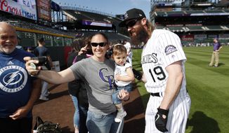Colorado Rockies outfielder Charlie Blackmon, right, stops for a photo with Stephanie Archuleta, center, and her 20-month-old daughter Javielyn during a fan photo promotion before a baseball game against the Toronto Blue Jays, Saturday, June 1, 2019, in Denver. (AP Photo/David Zalubowski)