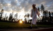 In a white cap and gown a graduating senior walks to the graduation ceremonies at Paradise High School in Paradise, Calif., Thursday, June 6, 2019. (AP Photo/Rich Pedroncelli)