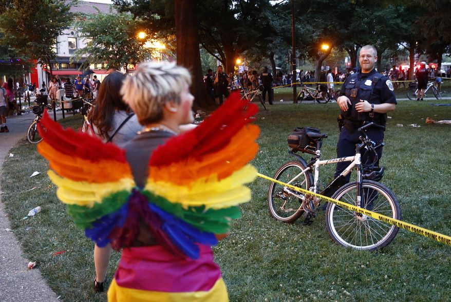 A police officer stands behind crime scene tape, Saturday, June 8, 2019, at Dupont Circle in Washington. Officials in Washington say several people were injured after a panic at the LGBTQ pride parade sent people running through the streets of the nation's capital. (AP Photo/Patrick Semansky)