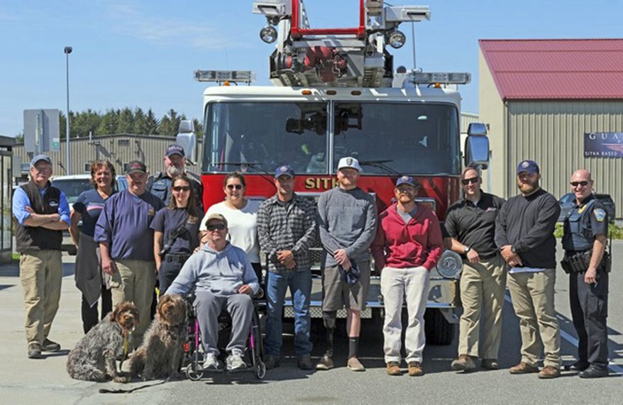 In this Saturday, May 25, 2019 photo, military veterans from Freedom Alliance are greeted at the Sitka, Alaska, airport by local fire and police personnel as they start a week of adventure at Vonnie's Charters and Halibut Point Lodge. Often overlooked in conflicts that occur thousands of miles away on continents most people see just on social media, are the military veterans who return to their non-service lives with traumas both visible and unseen. A local fishing charter business, working with a veteran support organization called Freedom Alliance, has been reaching out to these veterans over the past several years, giving them a taste of all that Alaska has to offer. (Klas Stolpe/Sitka Sentinel via AP)