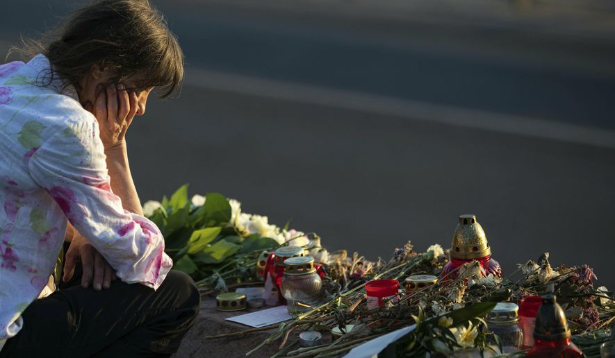 A woman visits a flower tributary at Margaret Bridge, the scene of the boat accident in Budapest, Hungary, Saturday, June 8, 2019. A sunken tour boat involved in a May 29 collision on the Danube River that killed at least 19 people is unlikely to be raised out of the water before Tuesday, Hungarian rescue officials said Saturday. (Balazs Mohai/MTI via AP)