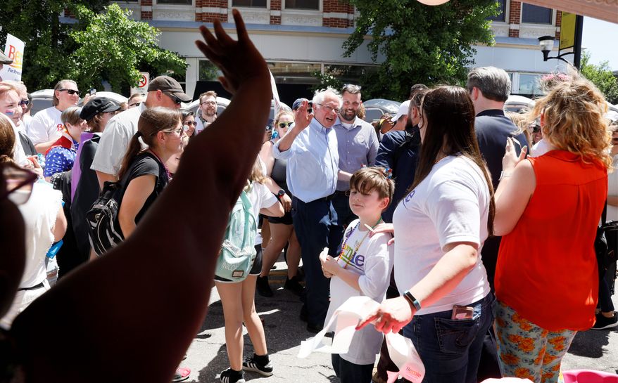 Democratic presidential candidate Bernie Sanders, center, waves to a vendor during the Capital City Pride Fest, on Saturday in Des Moines, Iowa. Mr. Sanders is running second, behind former Vice President Joseph R. Biden, in his bid for the nomination. (Associated Press)