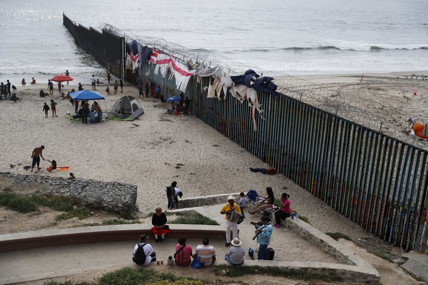 Musicians play music next to the U.S. border wall topped with razor wire in Tijuana, Mexico, Sunday, June 9, 2019. (AP Photo/Eduardo Verdugo)