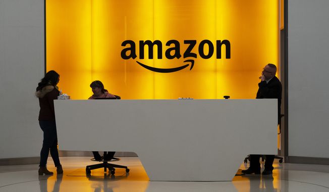 In this Feb. 14, 2019, file photo people stand in the lobby for Amazon offices in New York. (AP Photo/Mark Lennihan, File)