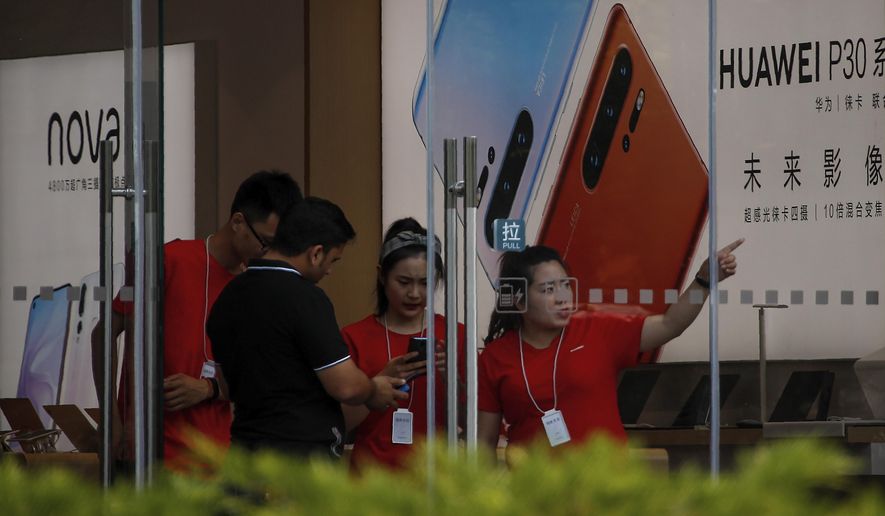 Staffers help a tourist search for directions at a Huawei retail store in Beijing, Tuesday, June 11, 2019. Chinese tech giant Huawei said Tuesday it would have become the world's number one smartphone maker by year's end if it were not for "unexpected" circumstances — a hint that pressure from the U.S. may be hurting its sales. (AP Photo/Andy Wong)