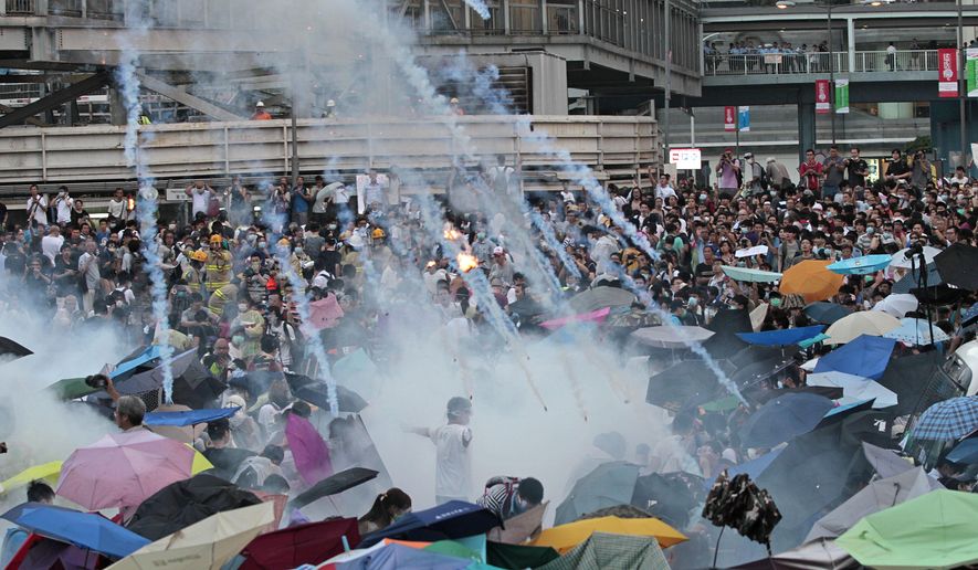 In this Sunday, Sept. 28, 2014, file photo, riot police launch tear gas into the crowd as thousands of protesters surround the government headquarters in Hong Kong. Hong Kong police used tear gas on Sunday and warned of further measures as they tried to clear thousands of pro-democracy protesters gathered outside government headquarters in a challenge to Beijing over its decision to restrict democratic reforms for the city. (AP Photo/Wally Santana, File)