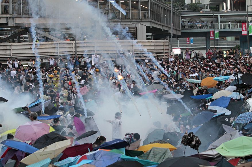 In this Sunday, Sept. 28, 2014, file photo, riot police launch tear gas into the crowd as thousands of protesters surround the government headquarters in Hong Kong. Hong Kong police used tear gas on Sunday and warned of further measures as they tried to clear thousands of pro-democracy protesters gathered outside government headquarters in a challenge to Beijing over its decision to restrict democratic reforms for the city. (AP Photo/Wally Santana, File)