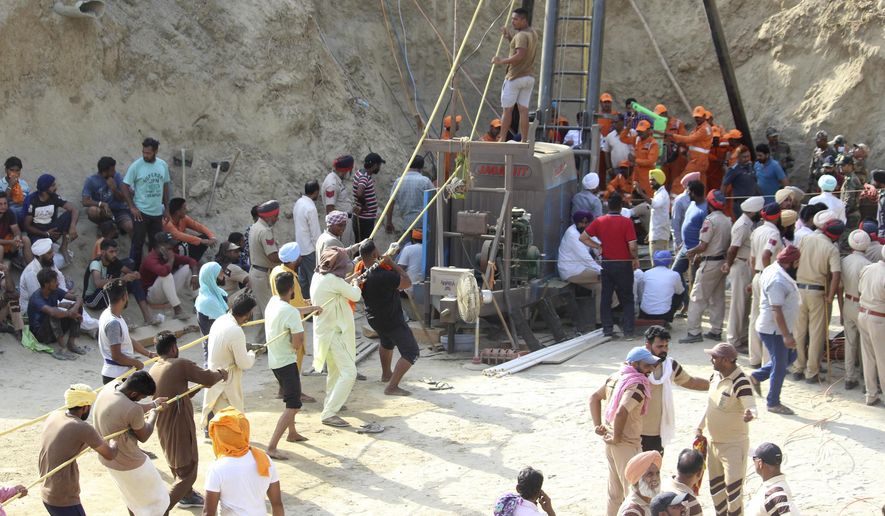 In this Monday, June 10, 2019 photograph, people try to rescue a 2-year-old boy who fell deep into an unused village well in Sangrur, Punjab state, India. The boy was brought to a hospital after he was removed from the well but doctors said he had died. The boy fell into the well last Thursday and state authorities dug a parallel well to save the boy. (AP Photo)