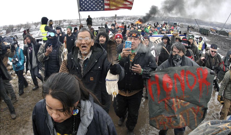 FILE - In this Feb. 22, 2017, file photo, a large crowd representing a majority of the remaining Dakota Access Pipeline protesters march out of the Oceti Sakowin camp before the deadline set for evacuation of the camp mandated by the U.S. Army Corps of Engineers near Cannon Ball, N.D. North Dakota's congressional delegation is urging two Trump administration officials to address the state's year-old demand for $38 million to cover the cost of policing large-scale and at times violent protests against the Dakota Access oil pipeline. (Mike McCleary/The Bismarck Tribune via AP, File)