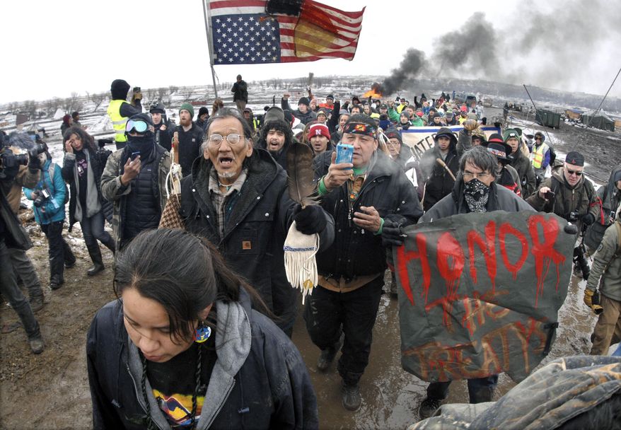 FILE - In this Feb. 22, 2017, file photo, a large crowd representing a majority of the remaining Dakota Access Pipeline protesters march out of the Oceti Sakowin camp before the deadline set for evacuation of the camp mandated by the U.S. Army Corps of Engineers near Cannon Ball, N.D. North Dakota's congressional delegation is urging two Trump administration officials to address the state's year-old demand for $38 million to cover the cost of policing large-scale and at times violent protests against the Dakota Access oil pipeline. (Mike McCleary/The Bismarck Tribune via AP, File)