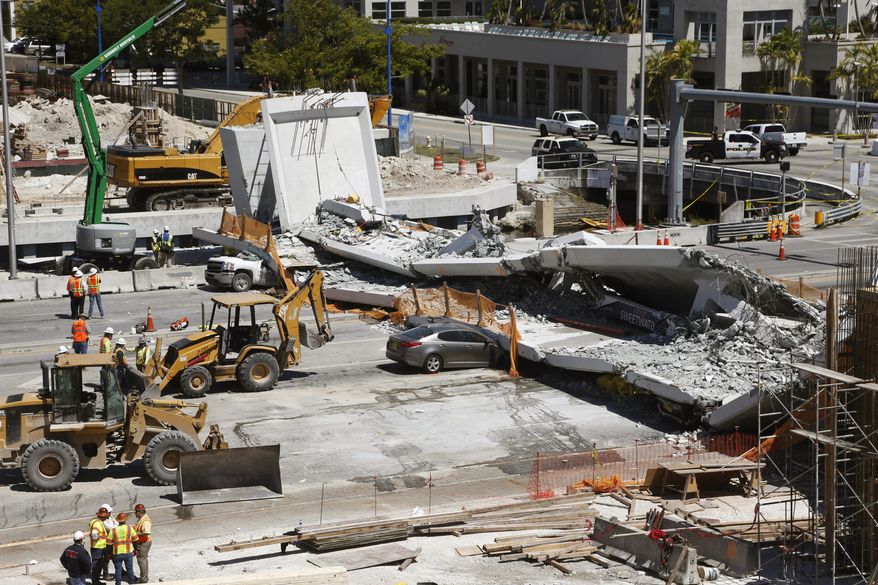 FILE - In this March 16, 2018 file photo crushed cars are shown under a section of a collapsed pedestrian bridge near Florida International University in the Miami area. A federal workplace safety agency says engineers had knowledge of extensive cracking and failed to order to close a street and shore up a pedestrian bridge before it collapsed and killed six people at a Miami university last year. On Tuesday, June 11, 2019 a report by the U.S. Occupational Safety and Health Administration concluded the size of the cracks warranted the street be shut down immediately. (AP Photo/Wilfredo Lee)