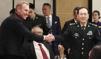 FILE - In this June 1, 2019, file photo, acting U.S. Secretary of Defense Patrick Shanahan, left, shakes hands with Chinese Minister of National Defense Gen. Wei Fenghe, right, during a ministerial luncheon on the sidelines of the 18th International Institute for Strategic Studies (IISS) Shangri-la Dialogue in Singapore. Shanahan sat down with his Chinese counterpart during his recent trip to Singapore and presented him with a photo book with a pointed message. The book looked like a coffee table book and was presented as a gift. But it was 32 pages of photos and satellite images of North Korean ships near China’s coastline involved in oil shipments that violate international sanctions. (AP Photo/Yong Teck Lim, File)