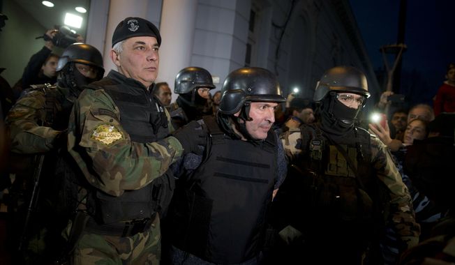 FILE - In this June 14, 2016 file photo, former Public Works Secretary Jose Lopez, center, is escort by police outside the a police station in the outskirts of Buenos Aires, Argentina. A court in Argentina sentenced Lopez on Wednesday, June 12, 2019, to 6 years in prison for illicit enrichment after he tried to hide millions of dollars in cash at a convent. (AP Photo/Natacha Pisarenko, File)