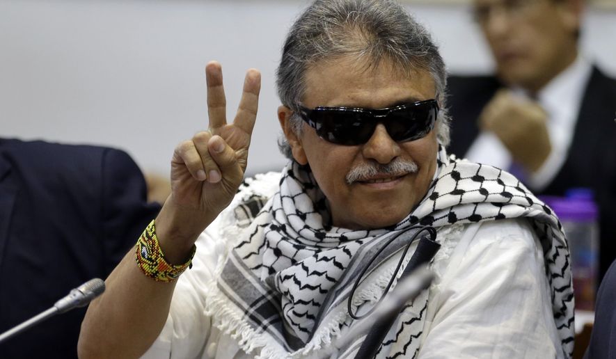 Former FARC rebel Jesus Santrich gives a victory signal to journalists as he attends a session of the Chamber of Representatives at the Colombian congress in Bogota, Colombia, Wednesday, June 12, 2019. Santrich was unable to take up his seat in congress last year when he was jailed awaiting extradition to the U.S. on drug charges, but was released in a decision by the special peace tribunal.(AP Photo/Fernando Vergara)