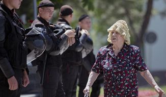An elderly woman walks by a line of riot policemen standing outside the government headquarters in Chisinau, Moldova, Wednesday, June 12, 2019. Moldova&#39;s police chief on Wednesday dismissed six officers who publicly backed a rival government, reflecting a continuing power struggle that has heightened political tensions in the impoverished ex-Soviet nation.(AP Photo/Roveliu Buga)