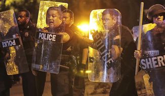 Memphis police brace against the crowd as protesters take to the streets of the Frayser community in anger against the shooting a youth by U.S. Marshals earlier in the evening, Wednesday, June 12, 2019, in Memphis, Tenn. (Jim Weber/Daily Memphian via AP)