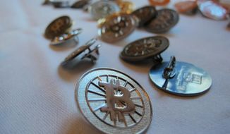 In this Feb. 12, 2014, photo Bitcoin buttons are displayed on a table at the Inside Bitcoins conference in Berlin. Researchers calculate that the electricity required for the virtual currency bitcoin generates as much carbon dioxide as cities like Las Vegas or Hamburg. (AP Photo/Frank Jordans) **FILE**