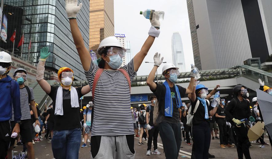 In this June 12, 2019, photo, demonstrators raise their hands near the Legislative Council in Hong Kong. (AP Photo/Kin Cheung, File)