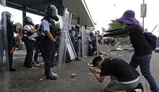 FILE - In this file photo taken Wednesday, June 12, 2019, a protester bows to riot police after they fire tear gas towards protesters outside the Legislative Council in Hong Kong. Hong Kong police have resorted to harsher-than-usual tactics to suppress protesters this week in the city’s most violent turmoil in decades. Police fired rubber bullets and beanbag rounds at the crowds, weapons that have not been widely used in recent history. (AP Photo/Vincent Yu, File)