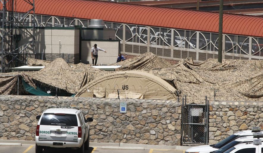 In this June 7, 2019, photo, migrants adjust a shade canopy over an outdoor encampment where they're waiting to be processed by immigration in El Paso, Texas. The Trump administration is facing growing complaints from migrants about severe overcrowding, meager food and other hardships at border holding centers like this one. (AP Photo/Cedar Attanasio)
